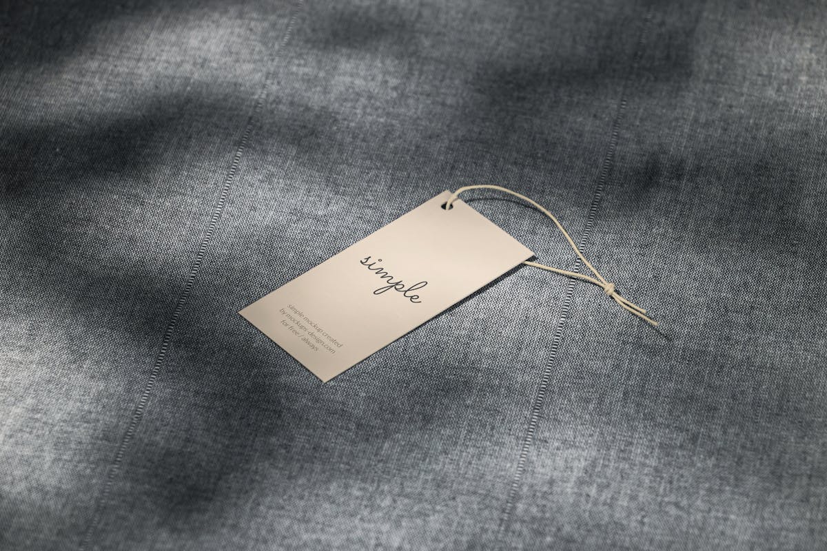 Blank clothing tag resting on neutral woven textile fabric.